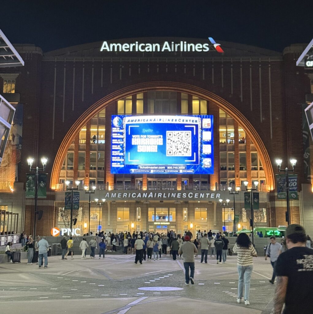 American Airlines Center at night in Victory Park downtown Dallas with crowds outside