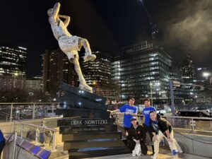 International investment group from Tokyo visiting downtown Dallas posing at Dirk Nowitzki statue in Victory Park