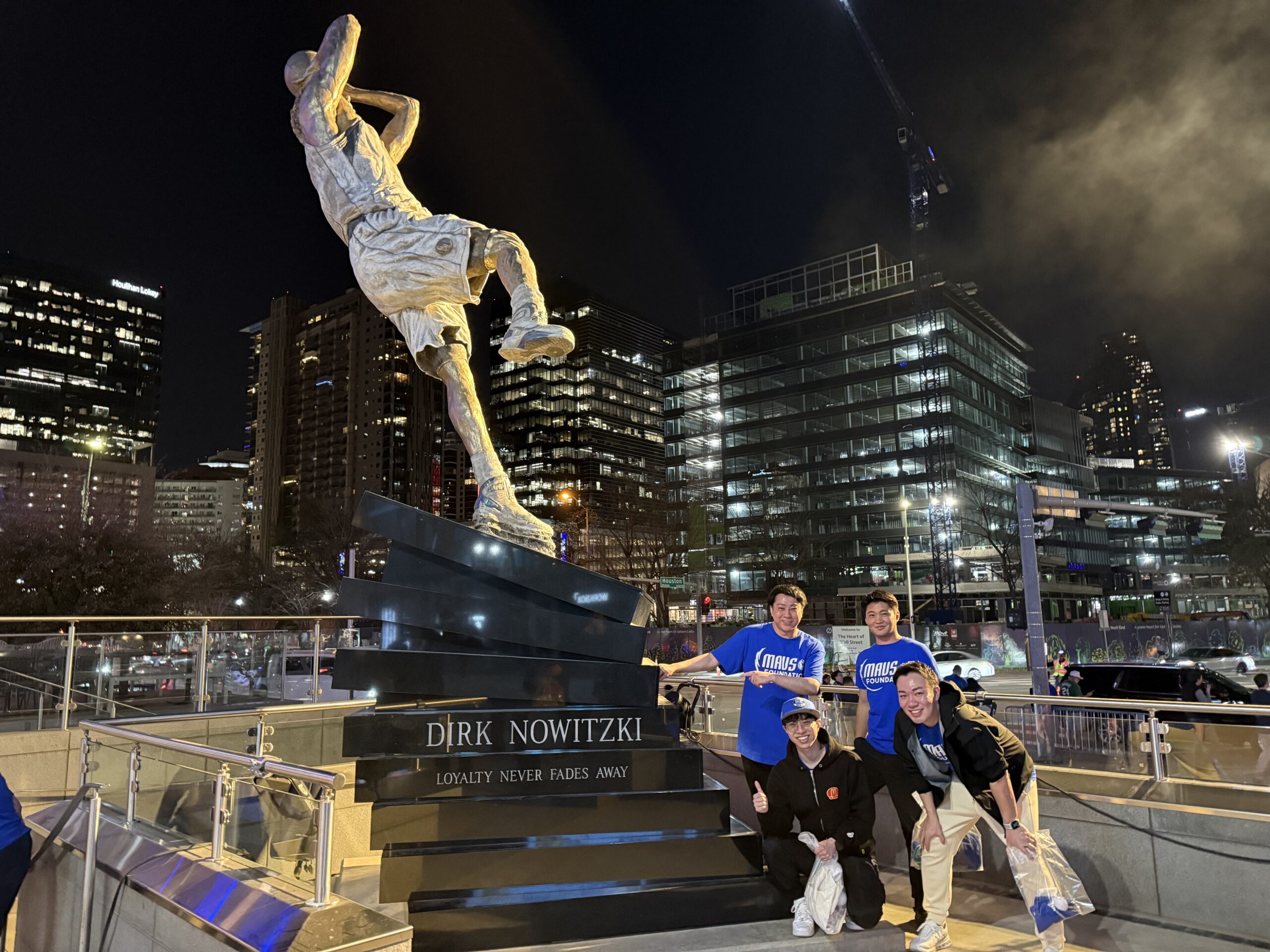 International investment group from Tokyo visiting downtown Dallas posing at Dirk Nowitzki statue in Victory Park